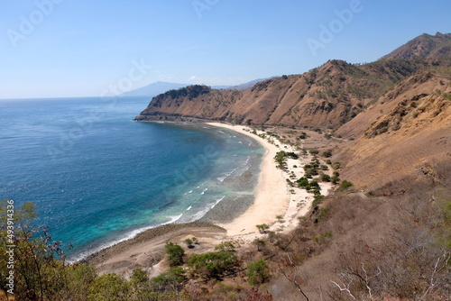The stunning curved white sandy beach and turquoise blue ocean of Cristo Rei back beach in Dili, Timor Leste