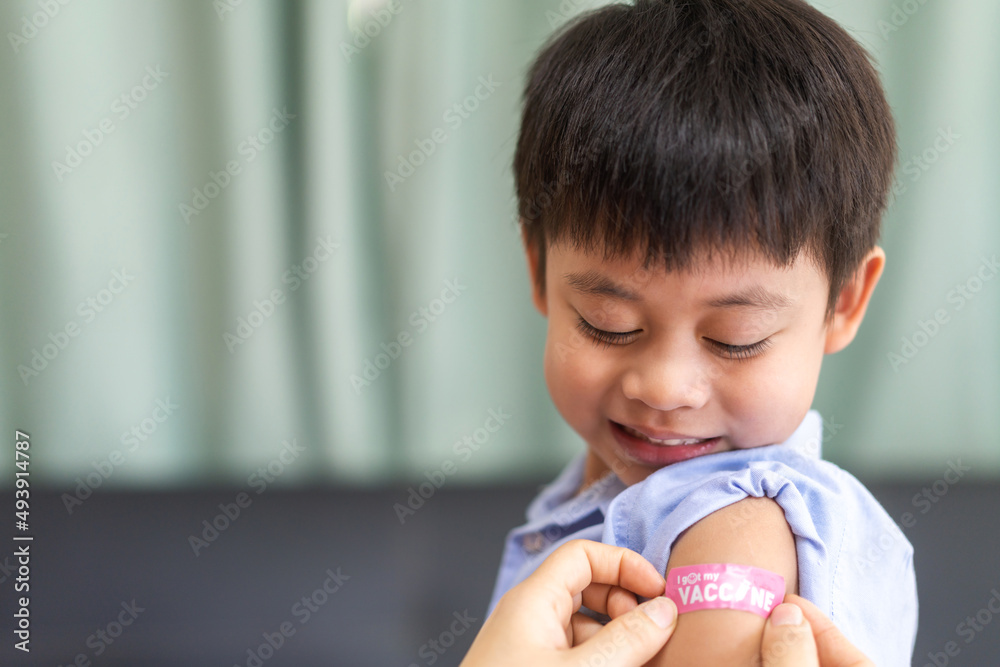 Portrait of happy smile vaccinated little asian kid boy children ages 5 to 11 years old posing show arm with medical plaster after Injection vaccine Covid-19 protection.coronavirus vaccination kid Portrait of happy smile vaccinated little asian kid boy children ages 5 to 11 years old posing show arm with medical plaster after Injection vaccine Covid-19 protection.coronavirus vaccination kid