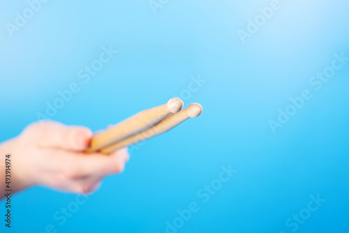 Close up male hands holding drumsticks on an isolated blue background. Concept of drumming lessons, online courses and learning at home. Favourite hobby. Background with copy space