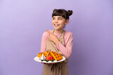 Little caucasian girl holding waffles isolated on purple background intending to realizes the solution while lifting a finger up