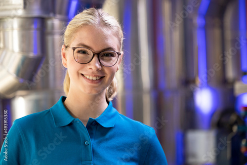 Smiling technician wearing eyeglasses standing in factory photo