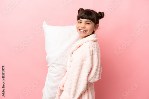 Little caucasian girl isolated on pink background in pajamas and smiling a lot