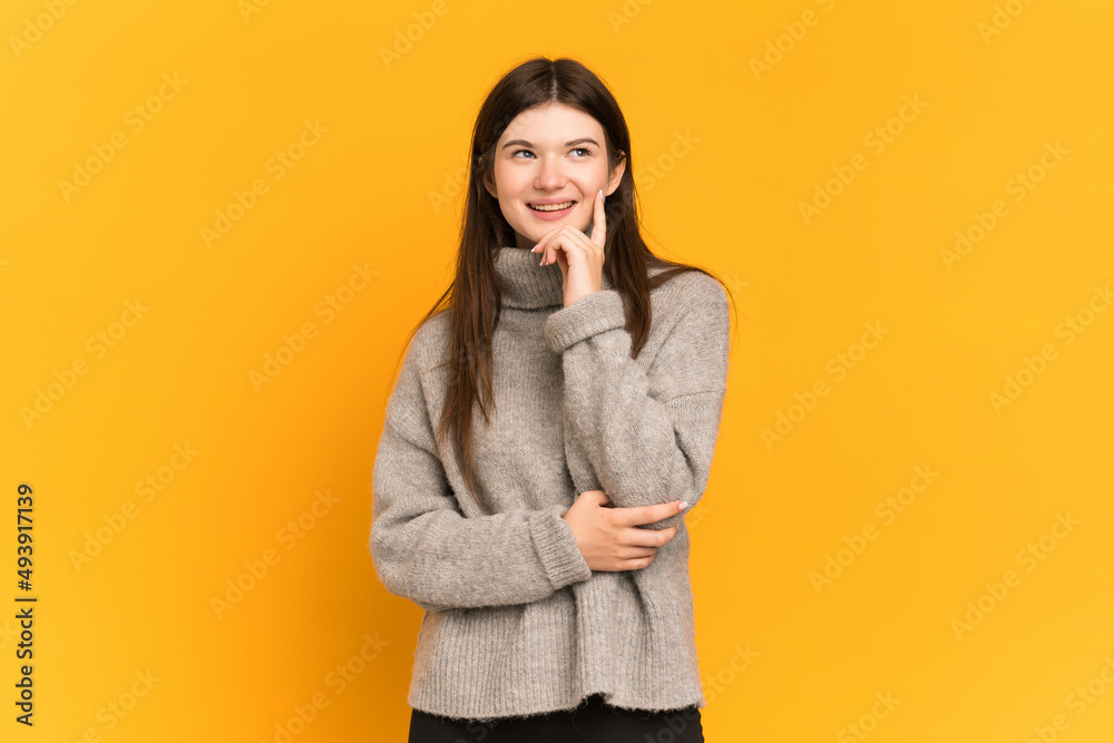 Young Ukrainian girl isolated on yellow background thinking an idea while looking up Young Ukrainian girl isolated on yellow background thinking an idea while looking up