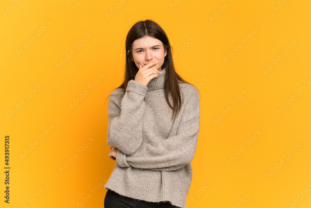 Young Ukrainian girl isolated on yellow background having doubts and with confuse face expression Young Ukrainian girl isolated on yellow background having doubts and with confuse face expression