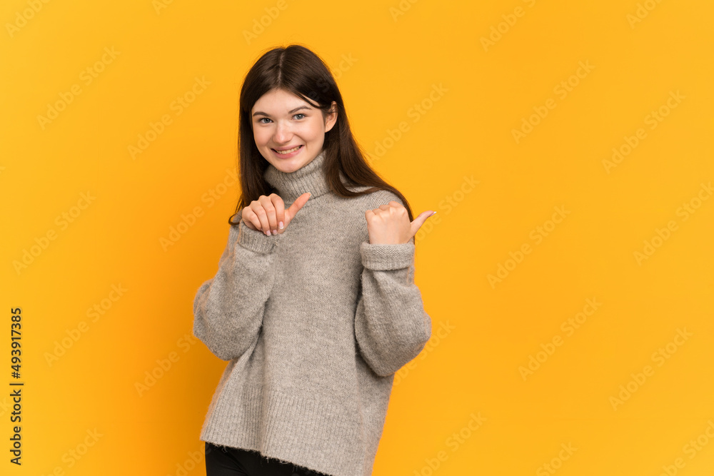 Young Ukrainian girl isolated on yellow background pointing to the side to present a product Young Ukrainian girl isolated on yellow background pointing to the side to present a product