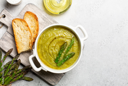 Cream of asparagus soup, vegan. Prepared with asparagus, potato, onion, vegetable stock and olive oil. Toast bread, uncooked ingredient on bacground. Copy space.