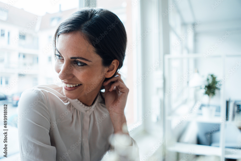 Happy businesswoman with hand in hair at work place Happy businesswoman with hand in hair at work place