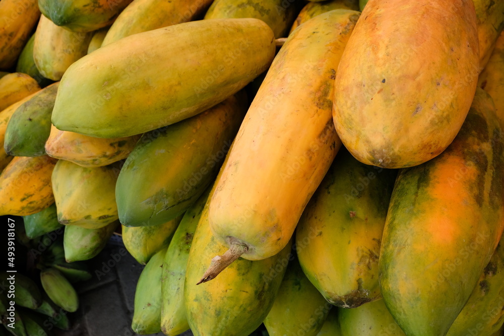 Massive fresh papaya tropical fruits stacked in piles at the local