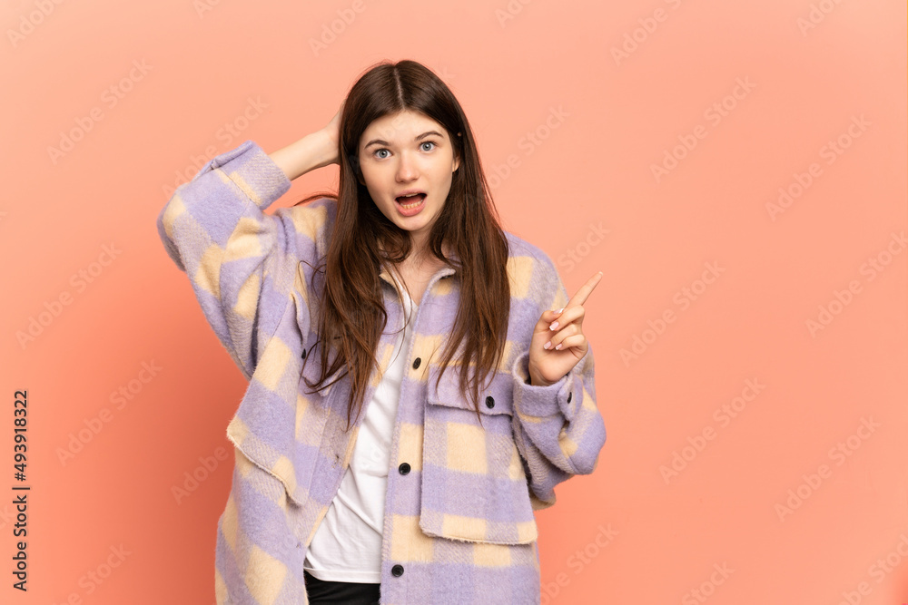 Young Ukrainian girl isolated on pink background surprised and pointing finger to the side Young Ukrainian girl isolated on pink background surprised and pointing finger to the side