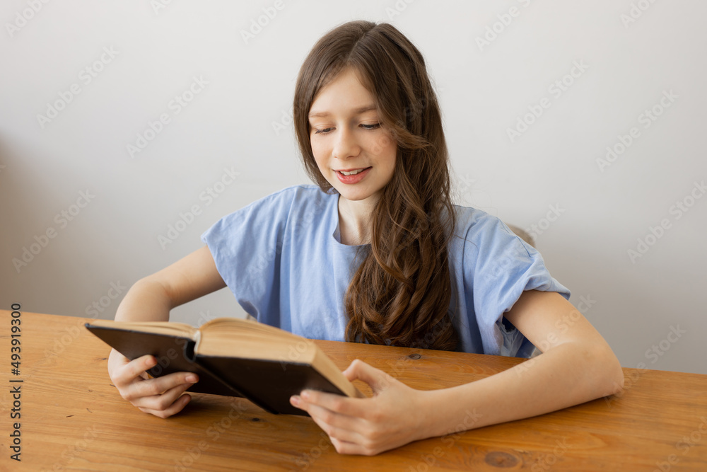 portrait of a cute happy teen girl at the table with a book portrait of a cute happy teen girl at the table with a book