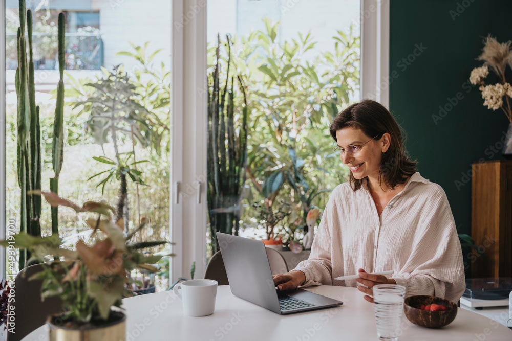 Smiling freelancer working with laptop on desk at home office