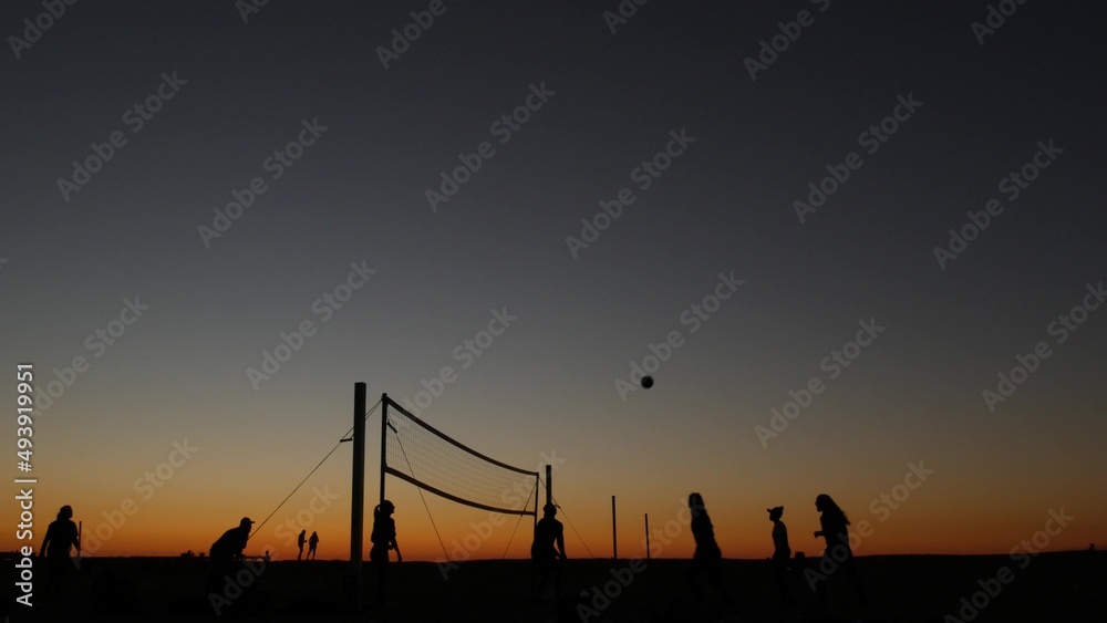 Fototapeta premium Volleyball net silhouette on beach sport court at sunset, people playing on California coast, USA. Sport field for volley ball game players by ocean shore. Twilight sky of Mission beach, San Diego.