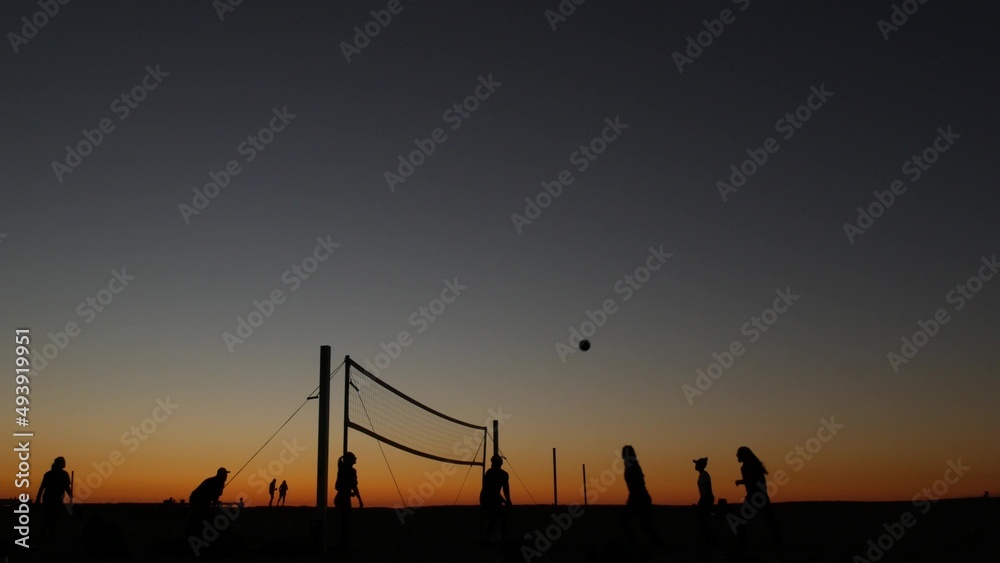 Volleyball net silhouette on beach sport court at sunset, people playing on California coast, USA. Sport field for volley ball game players by ocean shore. Twilight sky of Mission beach, San Diego.