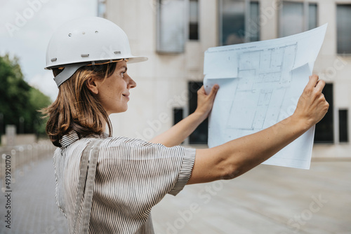 Architect with hard hat looking at blueprint photo
