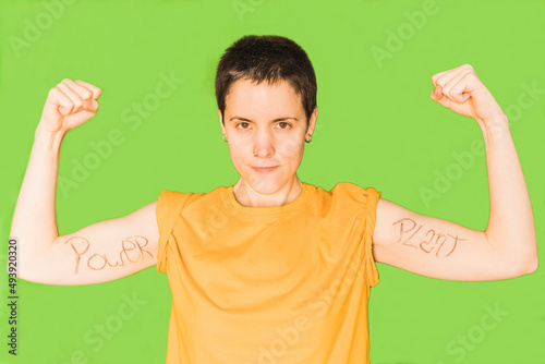 Woman with short hair flexing muscles against green background