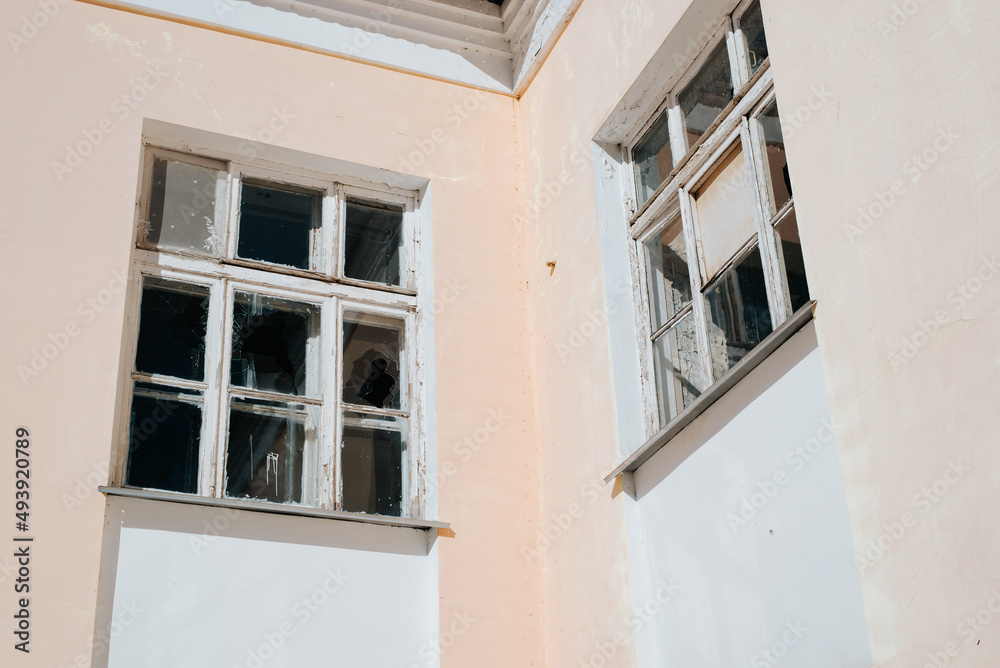 Facade of an abandoned building, broken glass windows, exterior of an old house outdoors Facade of an abandoned building, broken glass windows, exterior of an old house outdoors