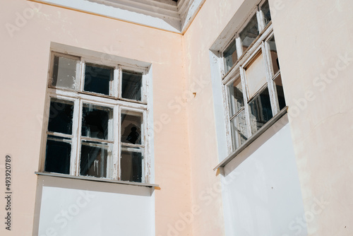 Facade of an abandoned building, broken glass windows, exterior of an old house outdoors
