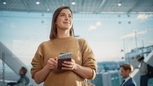 Airport Terminal: Happy Traveling Caucasian Woman Waiting at Flight Gates for Plane Boarding, Uses Mobile Smartphone, Checking Trip Destination on Internet. Smiling White Female on Vacation Trip