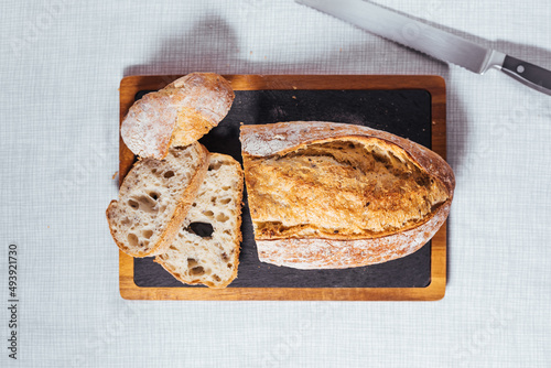 Loaf of sourdough bread on a bright background. Minimalist scene. Hands holding bread.
