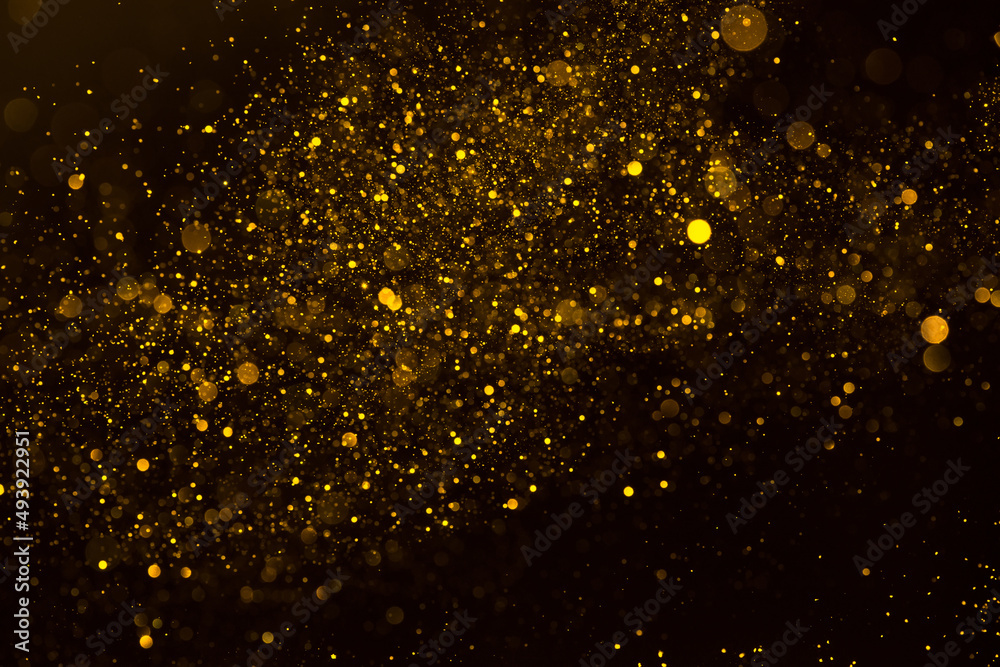 Abstract background of sparkling shiny golden glitter particles bokeh on black