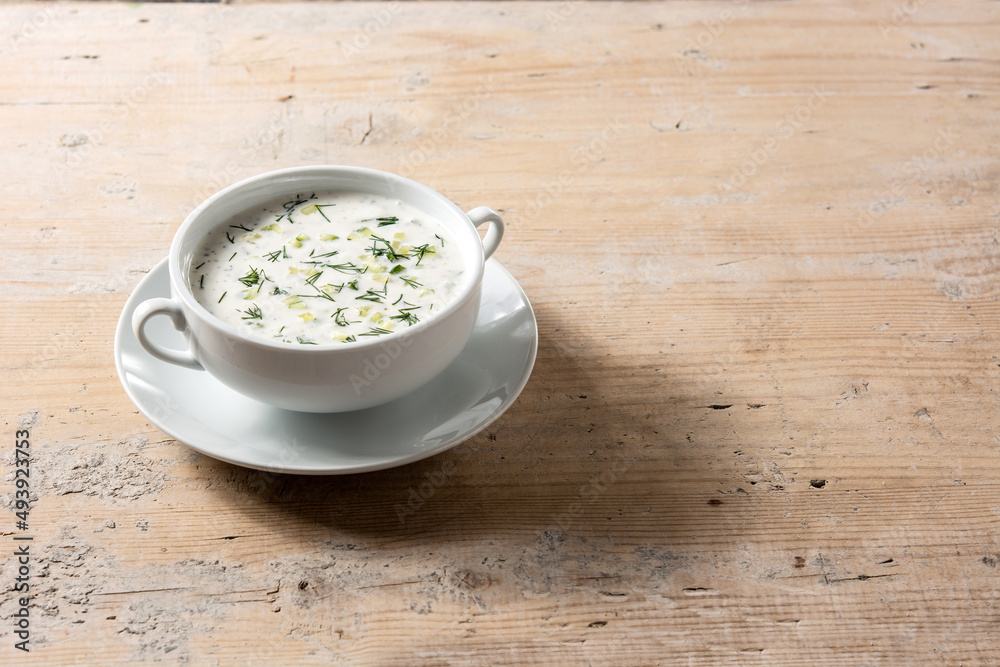 Bulgarian tarator sour milk soup in bowl on wooden table.Copy space Bulgarian tarator sour milk soup in bowl on wooden table.Copy space