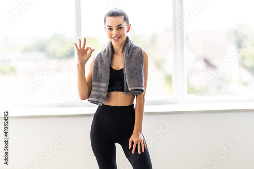Happy strong girl with towel on her shoulders. Fitness model isolated on white background. Sport and healthy lifestyle. © dianagrytsku