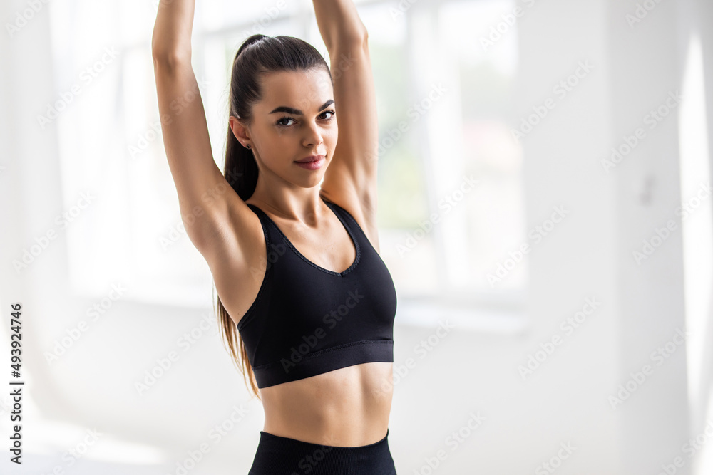 Fitness young woman in sportswear doing stretching exercise at gym.