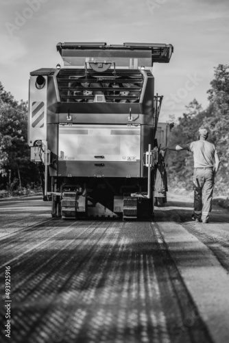 Operator of road milling machine removes asphalt from old road and loads milled asphalt in dump truck. 