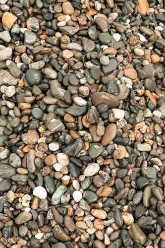 multi-colored pebbles on the seashore shimmers from the water in the sun free space close-up texture background