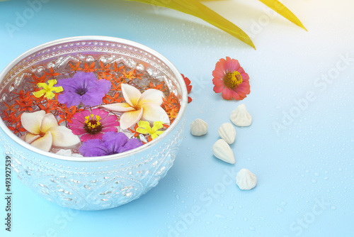 Thai songkran festival - Silver bowl with colorful flower and chalk powder on blue