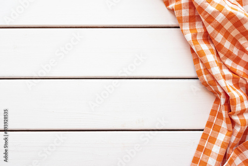 Checked orange tablecloth on white wooden background
