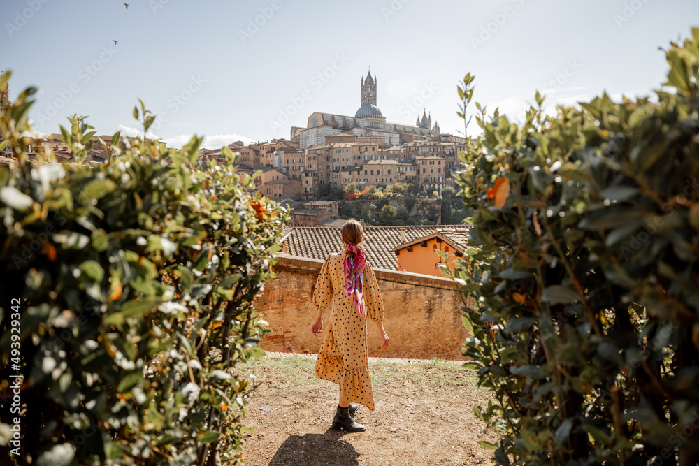 Stylish woman walks on background of cityscape of Siena old town. Concept of travel famous cities in Tosacny region of Italy - obrazy, fototapety, plakaty 