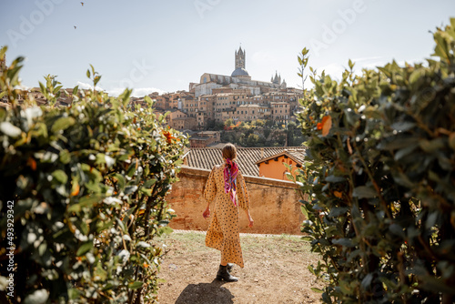 Canvas Print Stylish woman walks on background of cityscape of Siena old town