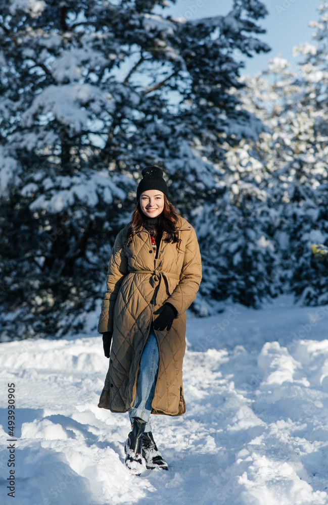 Fototapeta premium Smiling woman walks in forest in sunny winter day.