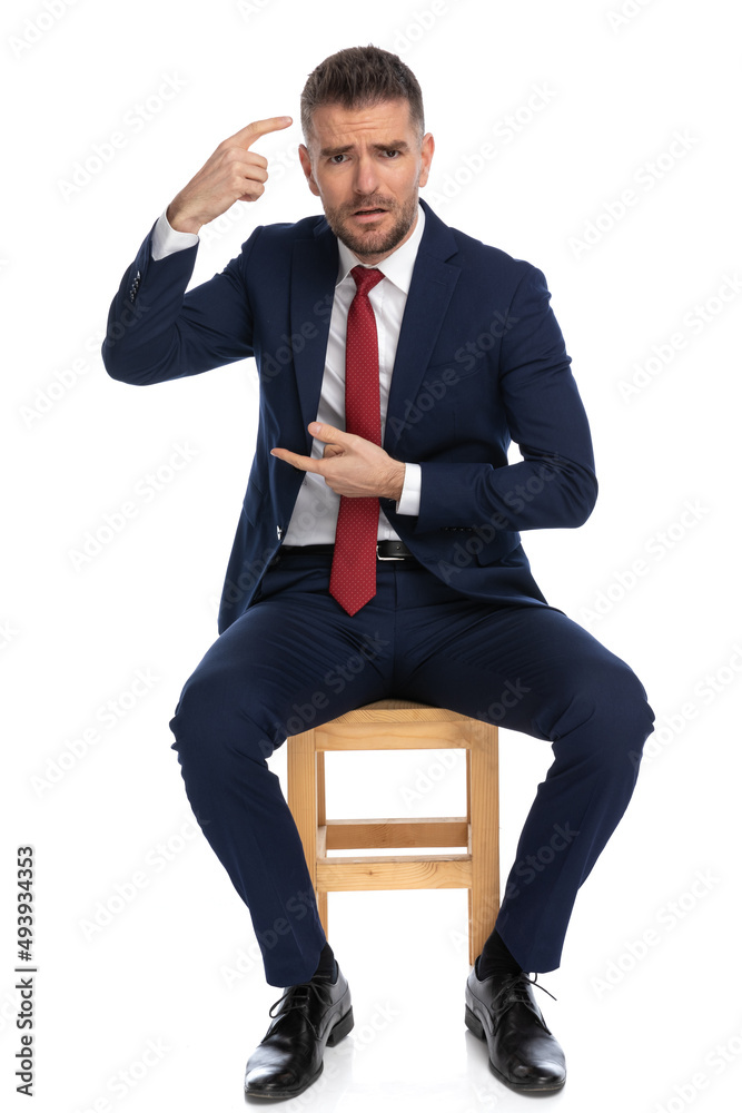 upset man in his forties pointing finger to head and blaming the idiot upset man in his forties pointing finger to head and blaming the idiot