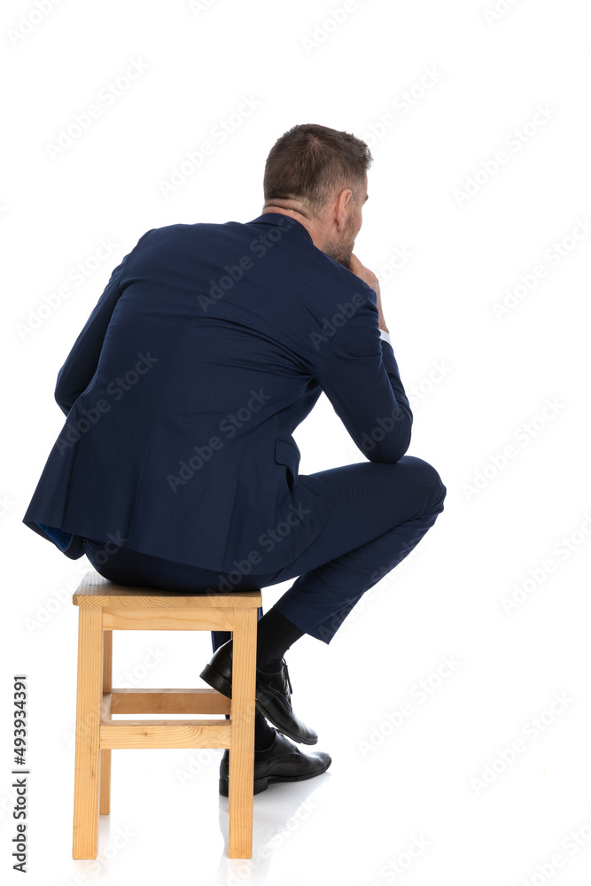 rear view of man in his forties holding hand to chin and thinking rear view of man in his forties holding hand to chin and thinking