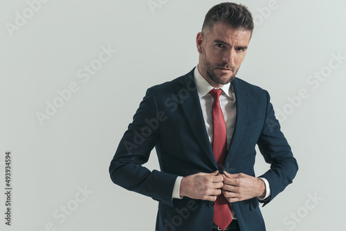 sexy middle aged guy adjusting and unbuttoning navy blue suit