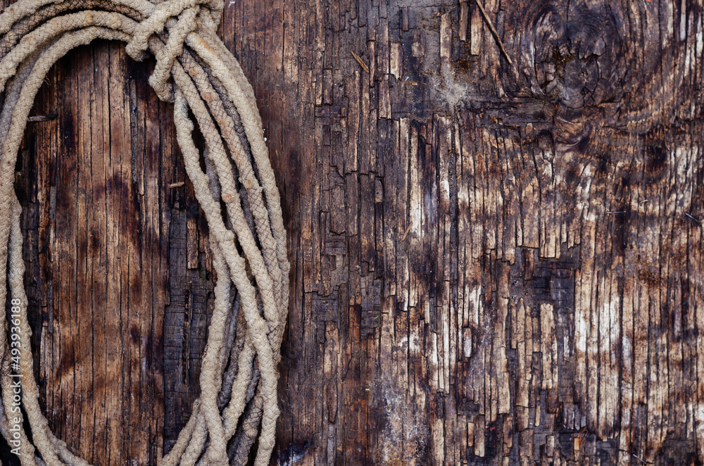 Coil of old rope on a dark wooden background. Worn, dirty rope.