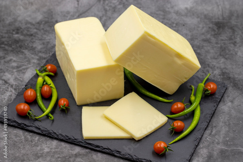 Cheddar cheese or kashkaval cheese on dark background. Cheese slices on the serving board photo