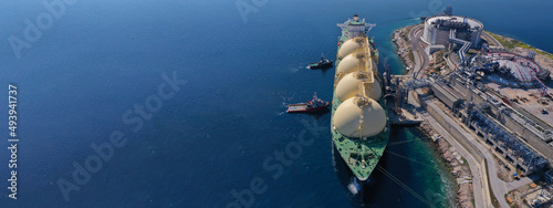 Aerial drone ultra wide panoramic photo with copy space of LNG (Liquified Natural Gas) tanker anchored in small gas terminal island with tanks for storage photo