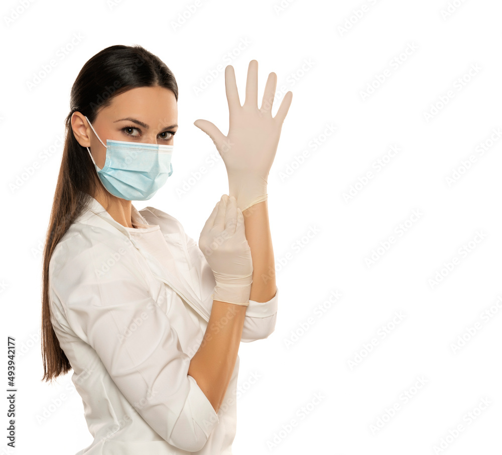 Beautiful female doctor or nurse wearing protective mask and latex or rubber gloves on white background with copyspace. Beautiful female doctor or nurse wearing protective mask and latex or rubber gloves on white background with copyspace.