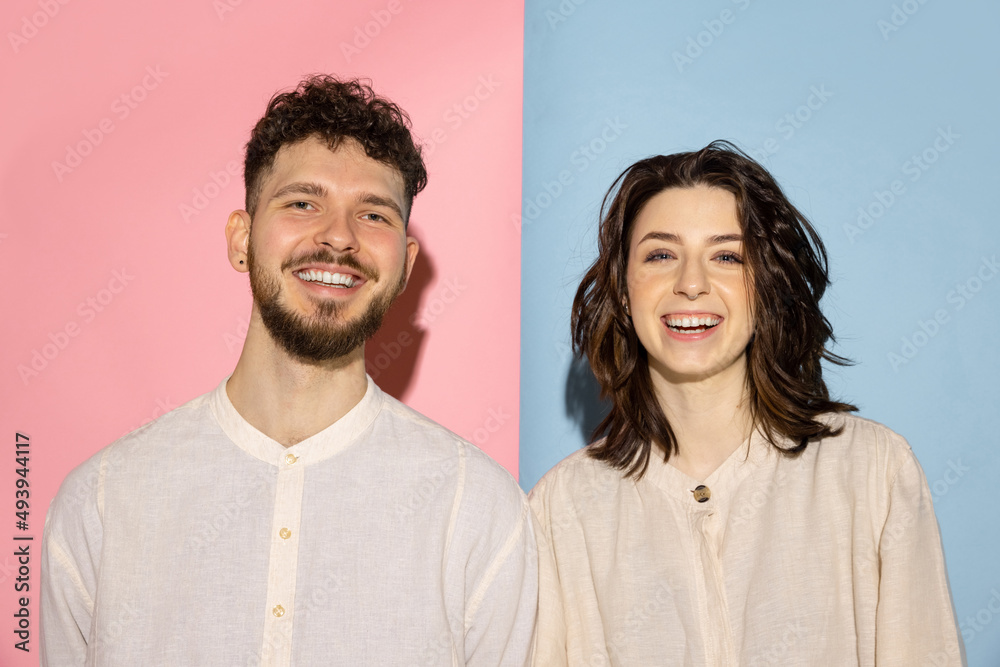 Half length portrait of young emotive man and girl looking at camera isolated on blue and pink trendy color background. Human emotions concept Half length portrait of young emotive man and girl looking at camera isolated on blue and pink trendy color background. Human emotions concept