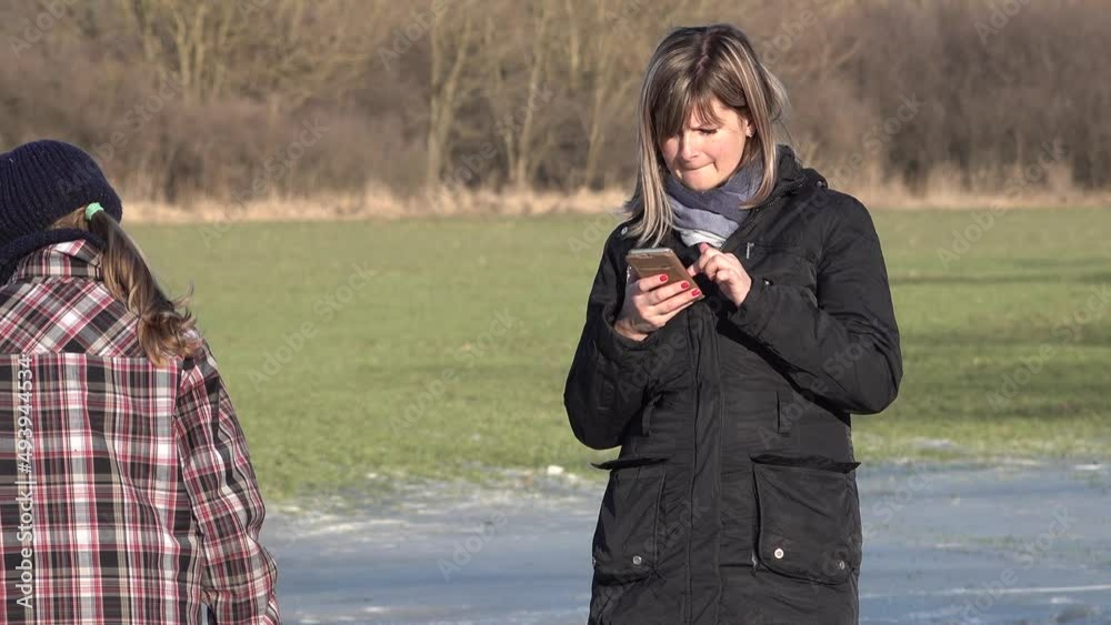 Young mother on ice, with her children, use applications in a smartphone. Young mother on ice, with her children, use applications in a smartphone.