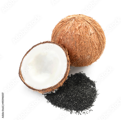 Ripe coconut with pile of activated carbon on white background