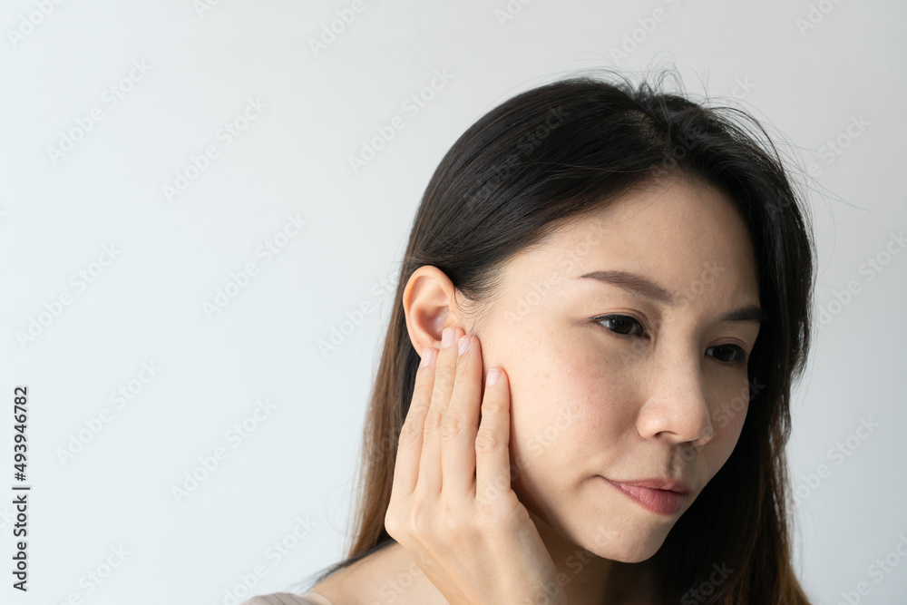 Young Asian woman with sore ear suffering from otitis over white background. Girl touch her ear with pain. Ear problem, health concept. Copy space, closeup Young Asian woman with sore ear suffering from otitis over white background. Girl touch her ear with pain. Ear problem, health concept. Copy space, closeup