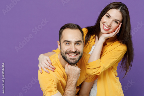 Young smiling happy fun nice lovely cheerful couple two friends family man woman 20s together wear yellow casual clothes looking camera hud cuddle isolated on plain violet background studio portrait