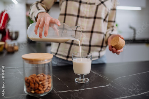 Photos Woman pouring almond milk into a glass in kitchen