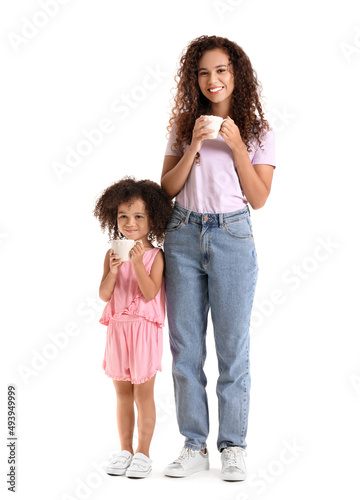 Little African-American girl and her mother with cups of hot cocoa on white background