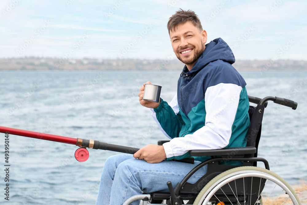 Man in wheelchair drinking tea while fishing on river Man in wheelchair drinking tea while fishing on river