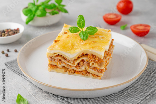 Slice of Lasagna bolognese with meat sauce and bechamel with melted cheese on top and fresh basil. Italian cusine. Copy space.